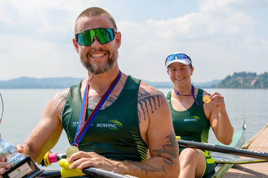 Two rowers with medals in a boat.