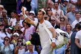 Tennis player Andy Murray walks off the court at Wimbledon carrying his bags and waving to the crowd.