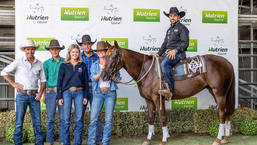 People stand gathered beside a horse at an auction.