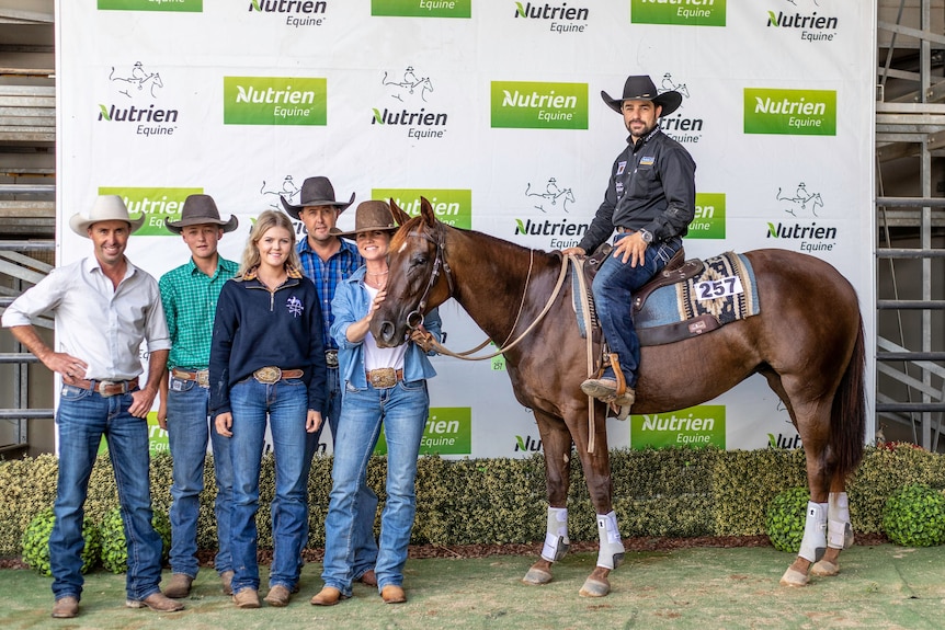 People stand gathered beside a horse at an auction.