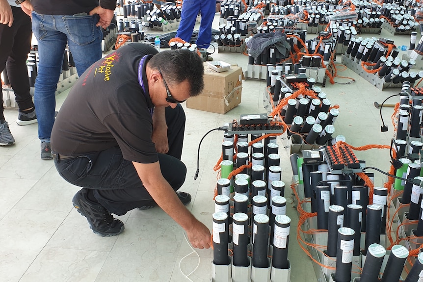 Mike Newman is leaning over a loaded and wired up firework mortar