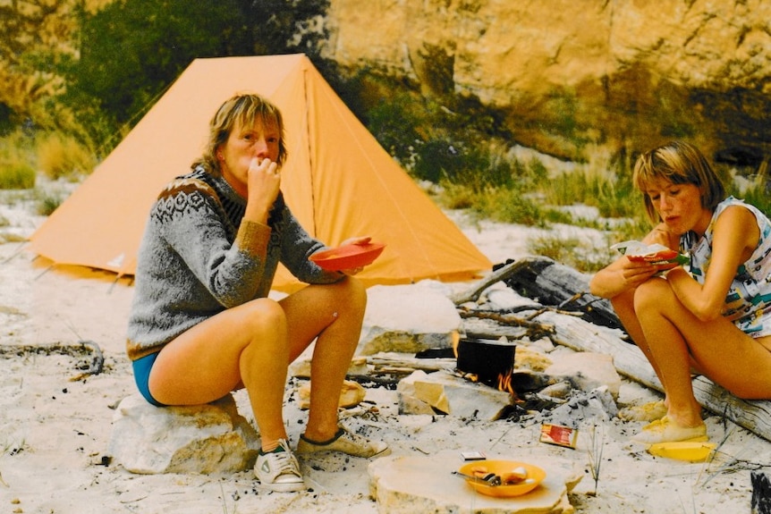 Celena Bridge (right) and her mum sitting and eating near a campfire.