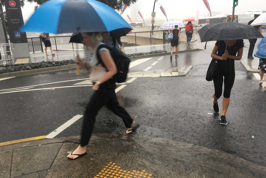 People walk with umbrellas across to southbank