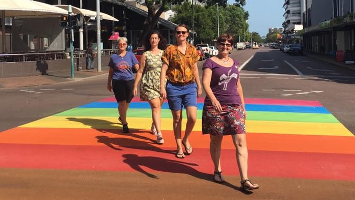 A white ute drives across a pedestrian crossing painted rainbow
