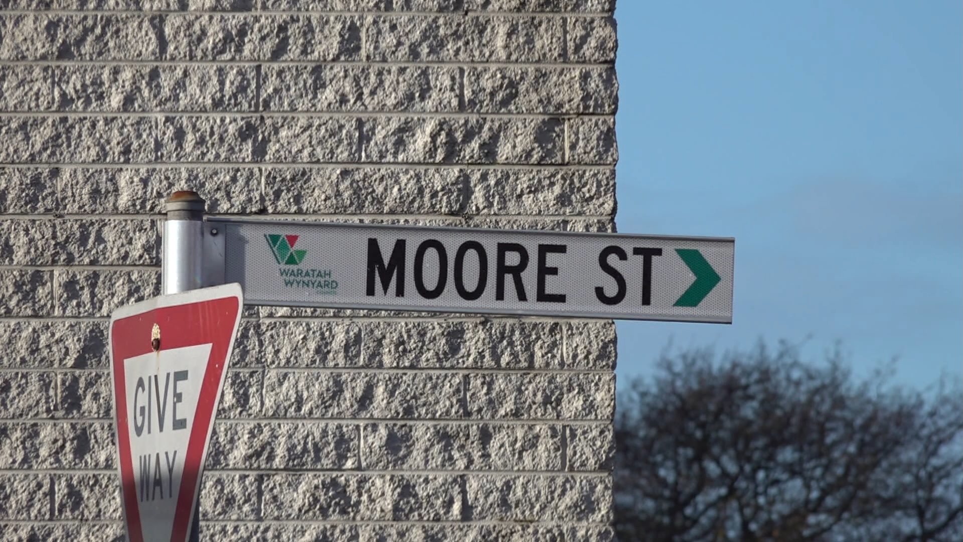 A street sign displaying 'Moore Street' attached to a give way sign.