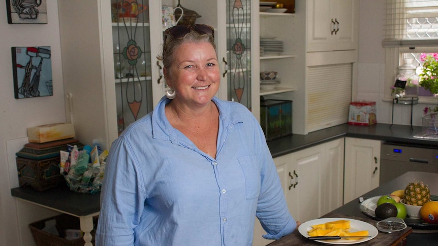 Woman smiling in the kitchen next to a plate of mango