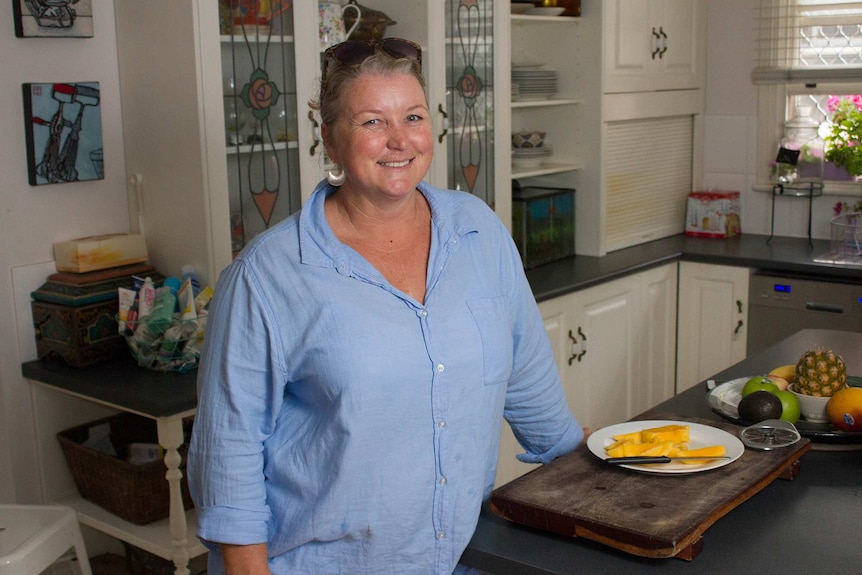 Woman smiling in the kitchen next to a plate of mango