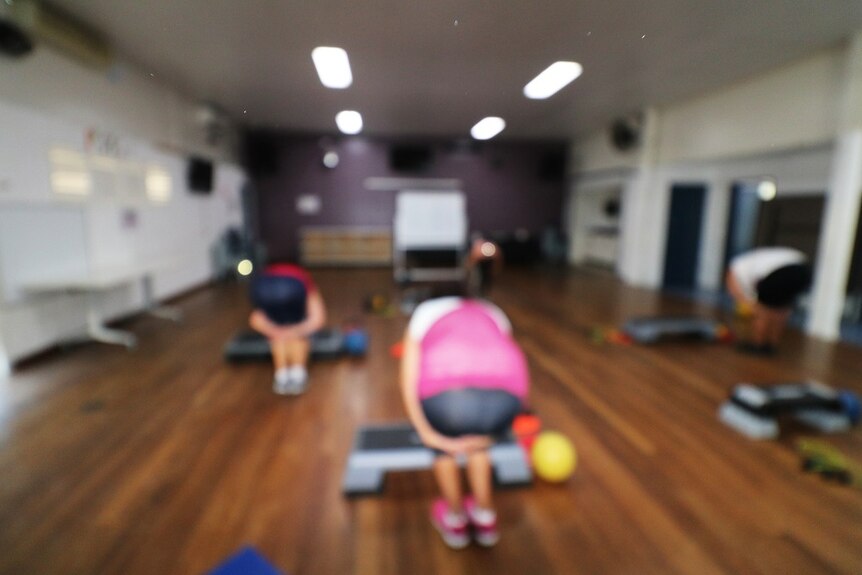 A blurry photo of women doing exercises in a hall