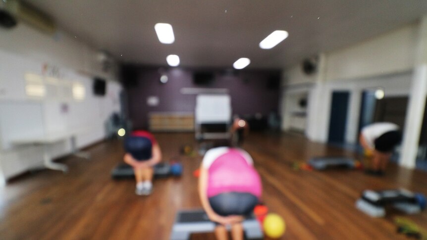 A blurry photo of women doing exercises in a hall