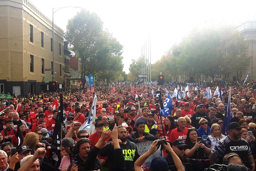 Thousands of people with union signs rally outside Trades Hall in Melbourne, calling for an increase to the minimum wage.