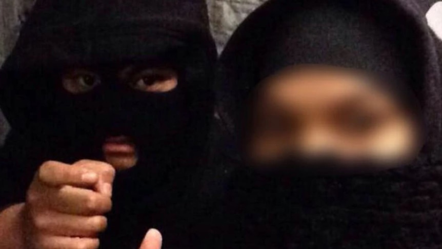 A man in a balaclava and a woman wearing a hijab and face covering