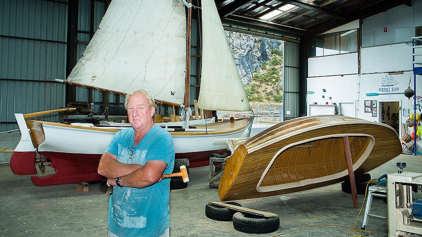 Man in shed with wooden boats