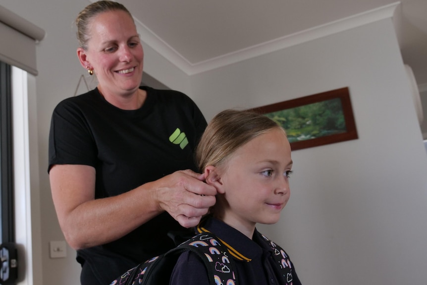 A mother does her daughter's hair for school