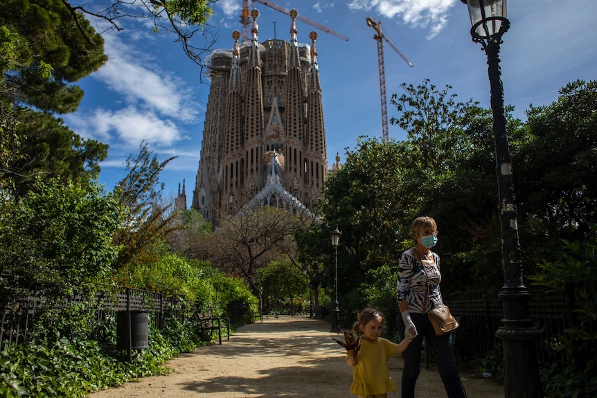 A woman walks with her granddaughter in a recently reopened park next to the Sagrada Familia church in Barcelona.
