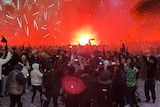 a large crowd gathering and letting off flares
