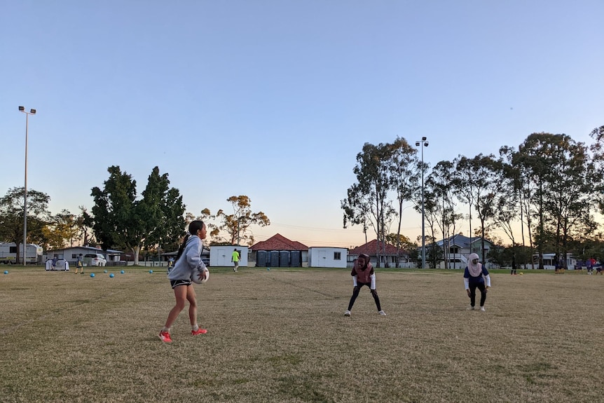 Some girls playing with a football in front of some portable changing rooms. 