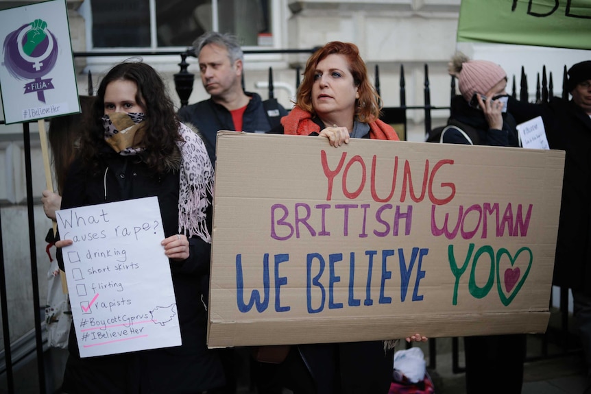 Protesters in London holding signs saying "Young British woman, we believe you".
