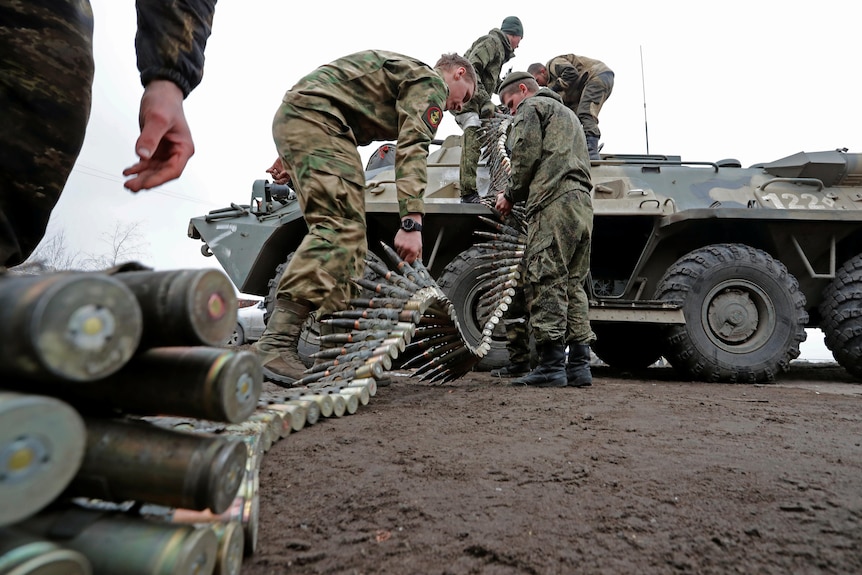 Service members of pro-Russian troops load ammunition into an armoured personnel carrier.