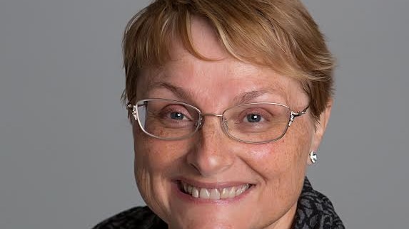 A head and shoulders image of a woman with glasses