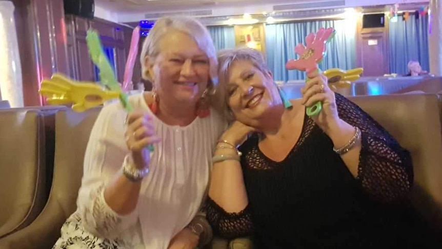 Two women celebrating with plastic hand toys.