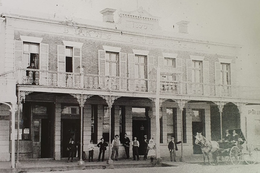 A black and white photo of a pub with people out the front and a horse and cart. 