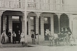 A black and white photo of a pub with people out the front and a horse and cart. 
