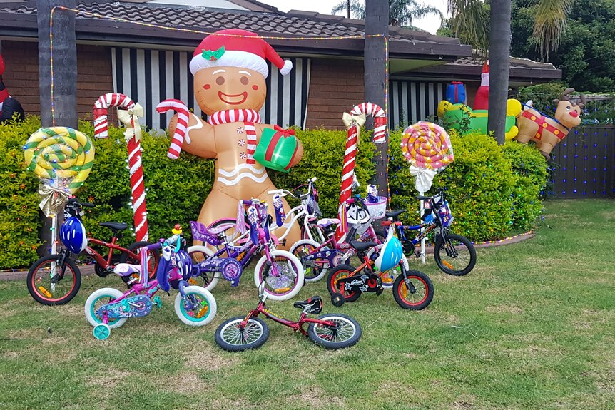 A house with large blow up Christmas decorations and 13 children's bikes in the lawn