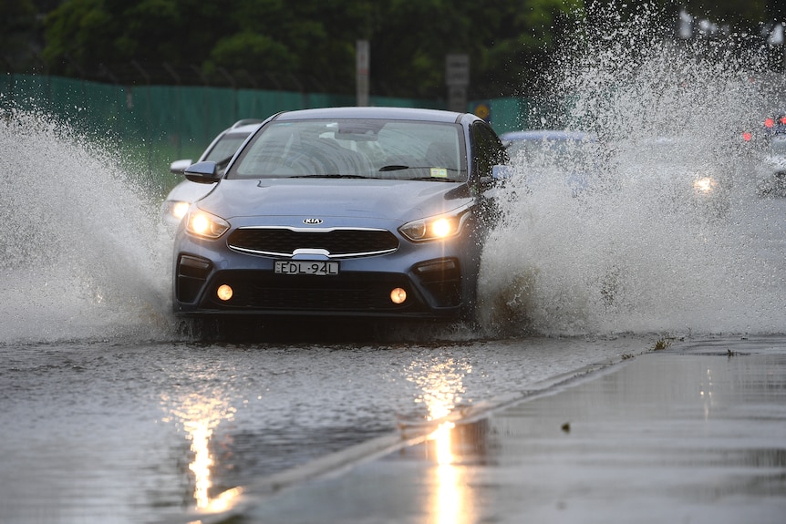 Car driving through pool of water on the road. 