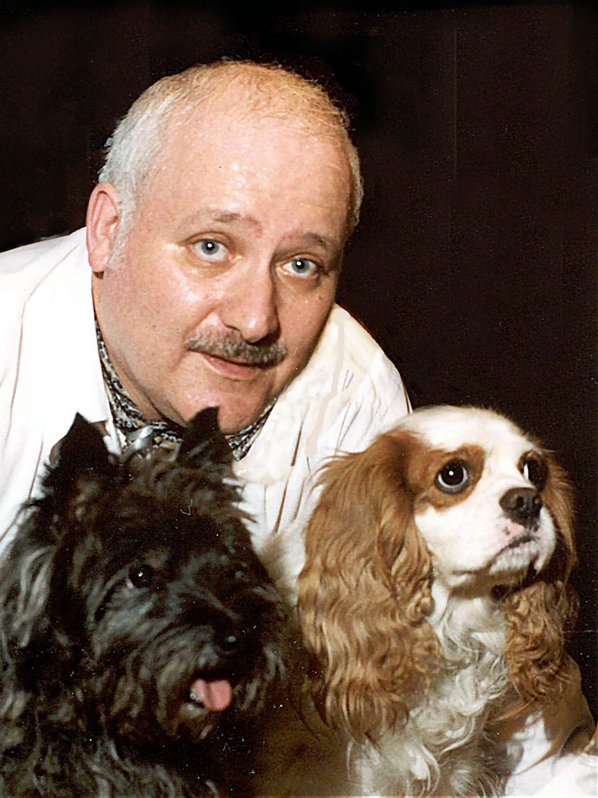 A man holds two little dogs