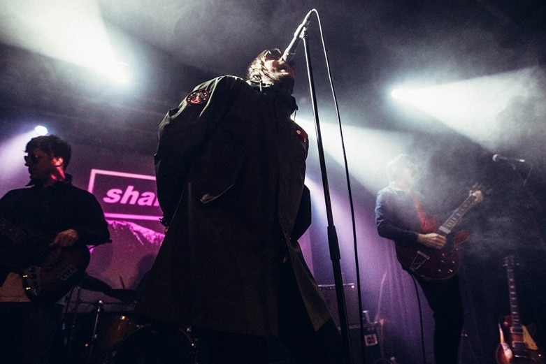 A man, seen from below, sings into a microphone on stage