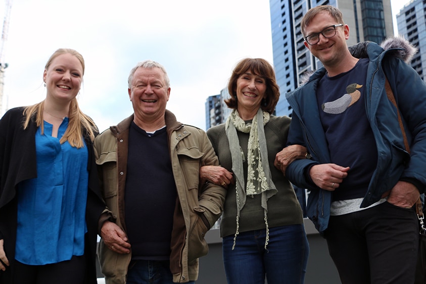 Phoebe Russell, Max McBride, Mairi Nicolson and Damien Eckersley stand linking arms and smiling in front of a Melbourne skyline.