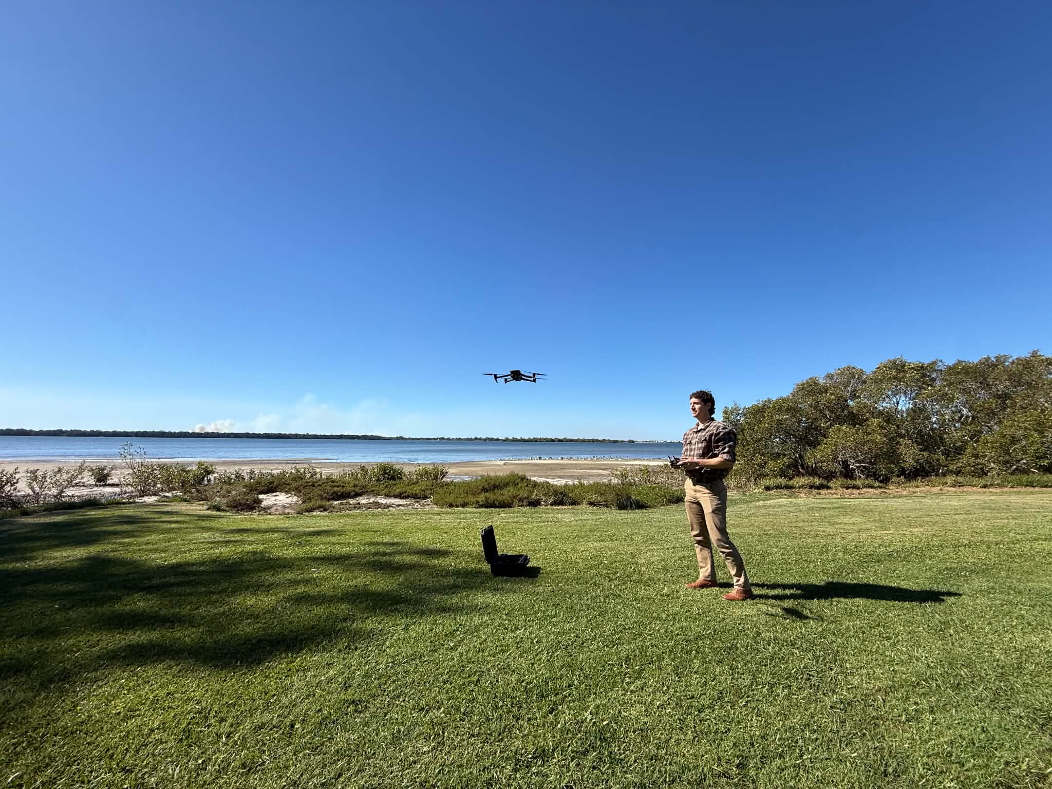 Man operating drone at shoreline