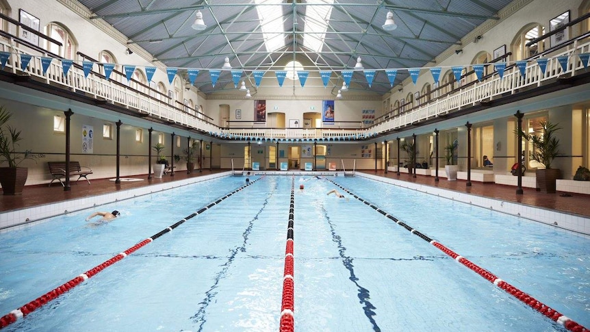 The interior of Melbourne's historic City Baths, with swimmers moving up and and down the 33-meter lanes
