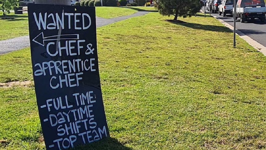 A chalk board with written chef and apprentice job vacancies set up on the roadside.