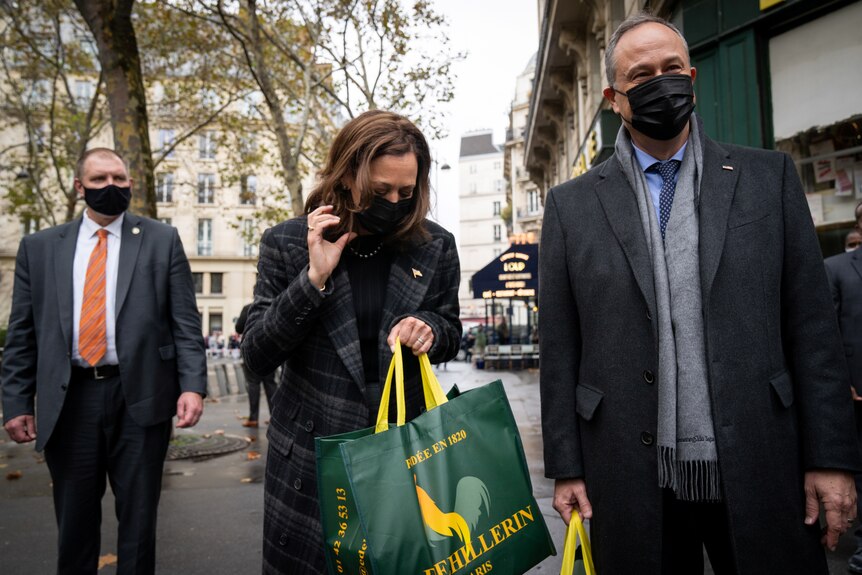 Kamala Harris carrying a big shopping bag on a Paris street next to her husband Doug Emhoff