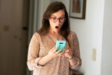 A woman gasps at her mobile phone screen after accidentally sending a message.