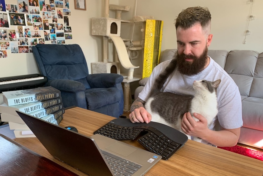 A bearded man cradles a cat