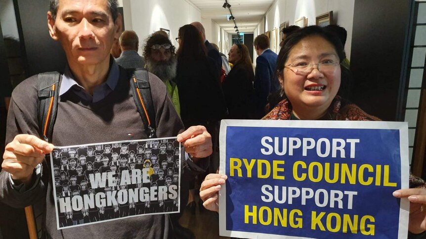 Two people hold signs in support of Ryde Council's solidarity with democracy protesters in Hong Kong
