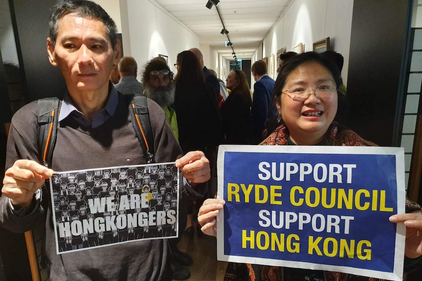 Two people hold signs in support of Ryde Council's solidarity with democracy protesters in Hong Kong