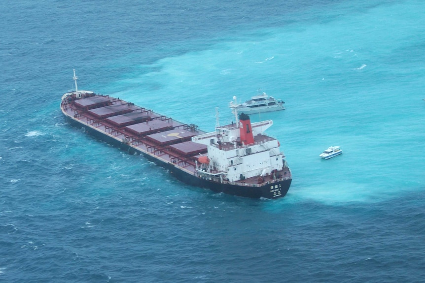 Ariel shot of a large coal carrier grounded on a part of the Great Barrier Reef surrounded by three other boats.