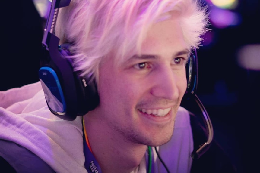 A young man with peroxide blonde hair wearing headphones