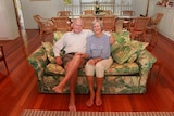Elderly couple sitting on their couch smiling