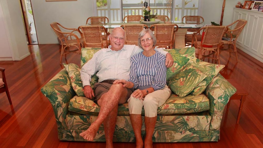 Elderly couple sitting on their couch smiling