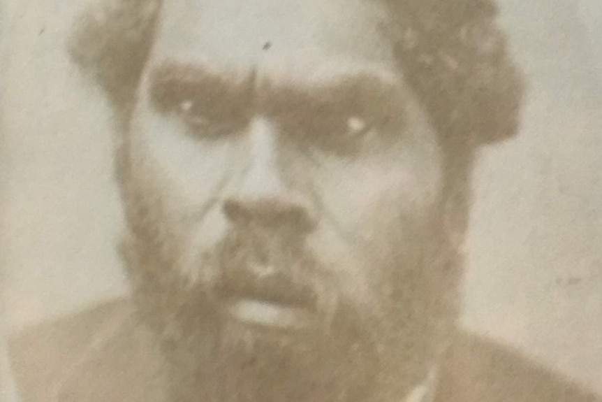 A black and white headshot of an Indigenous man with a beard