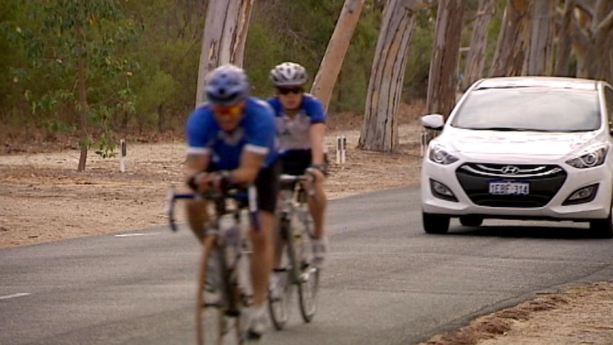 Two cyclists on road with car about to overtake
