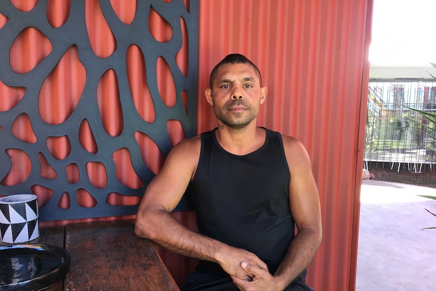 Daniel Gomes sitting at a table against a red and black wall