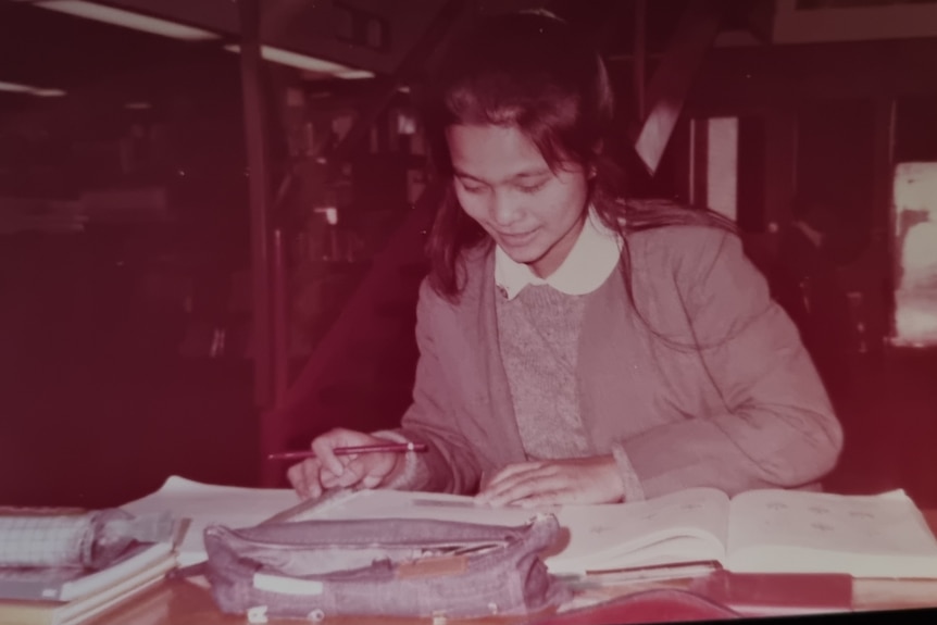 An old photo of a young teen girl looking at school books 