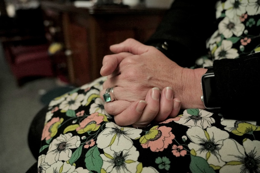 A woman's hands rest in her lap