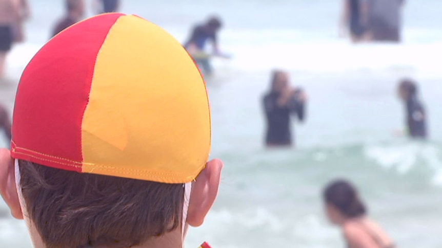 Back of a lifeguard's head looking at swimmers on Bondi Beach.