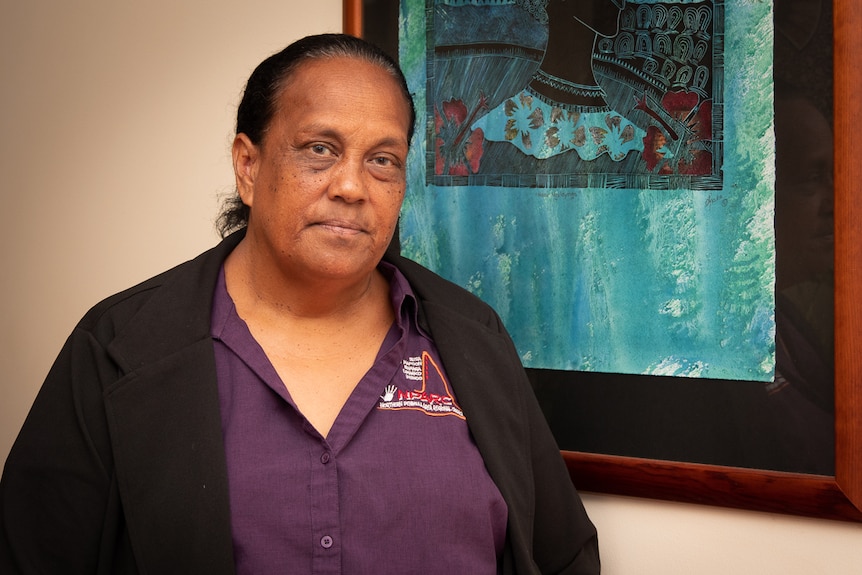 A woman stands in front of a blue painting